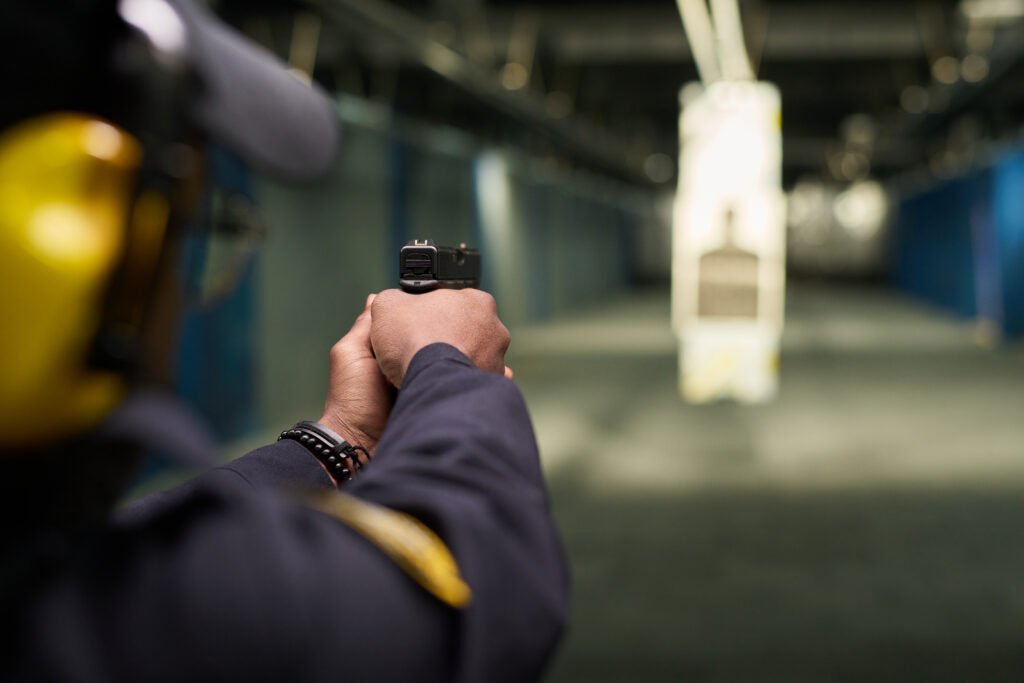 Close-up of individual aiming at target in indoor shooting range under professional supervision in controlled environment enhancing accuracy skills